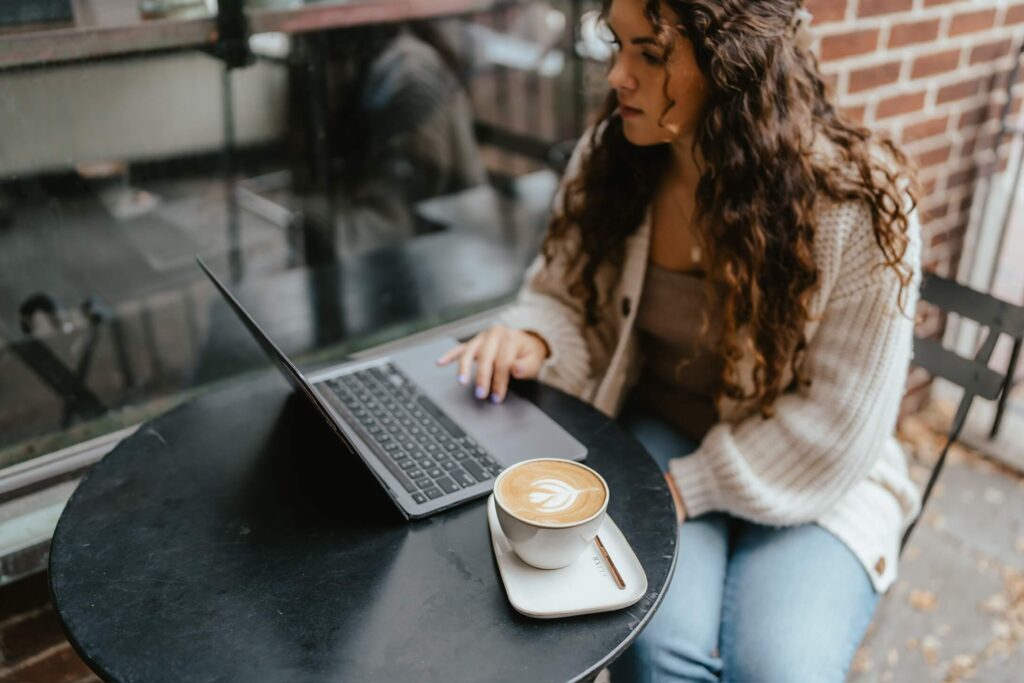 Small business owner working remotely at a coffee shop with a latte